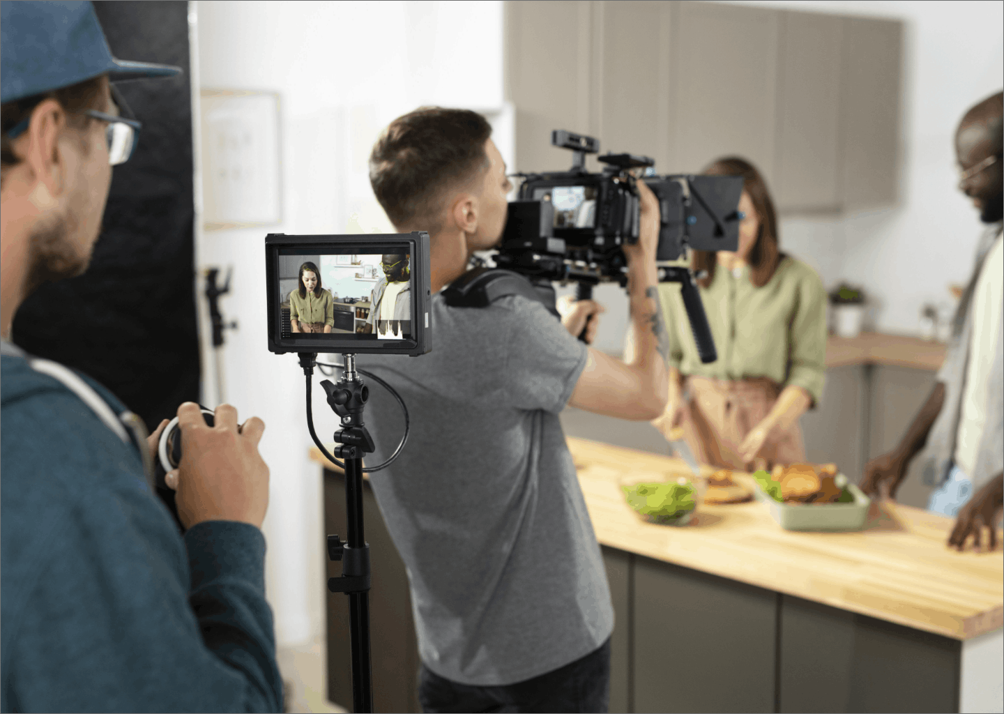 Camera crew filming a kitchen scene, with a production monitor in the foreground